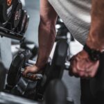 person in gray shirt holding black dumbbell